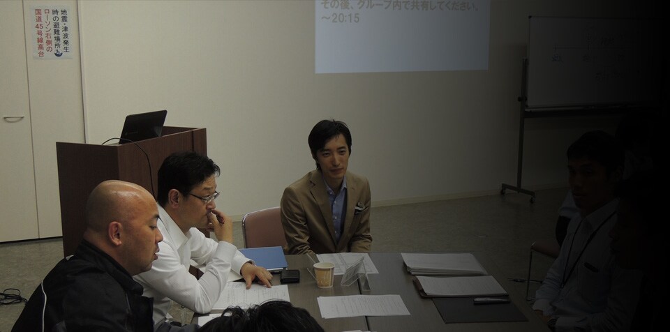 Fujii-san and other employees meet at a conference table so they can work together.