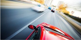 Rotes Auto auf einer verschwommenen Landstraße
