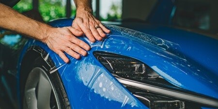 Person, die Lackschutzfolie auf einem Auto aufbringt
