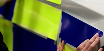 Person, die eine reflektierende Folie an einem Polizeiauto anbringt
