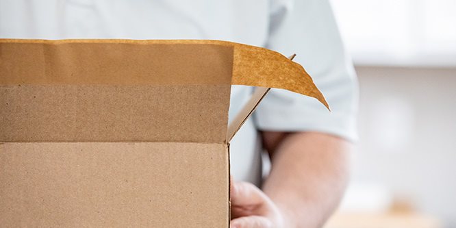 Person, die einen Karton mit Scotch Box Lock Papier-Verpackungsklebeband verschließt
