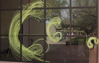 AltKarine Fellini’s artwork made from Scotch Performance Masking Tape. Green lines of tape create colorful artwork on a window.