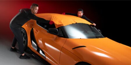 orangefarbene 3M Autofolie wird von zwei Verarbeitern angebracht
