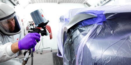 Ein Lackierer lackiert ein Auto mit einer 3M Lackierpistole
