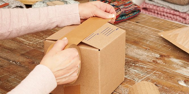 Person, die einen Karton mit Scotch® Box Lock™ Papier-Verpackungsklebeband verschließt
